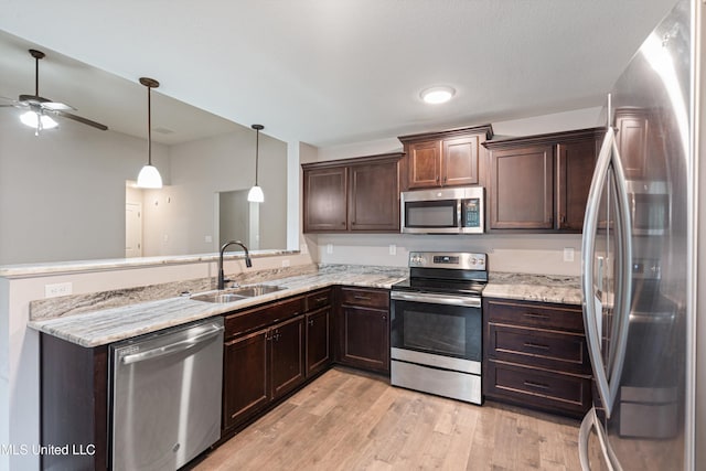 kitchen featuring appliances with stainless steel finishes, a sink, light wood-style flooring, and dark brown cabinetry