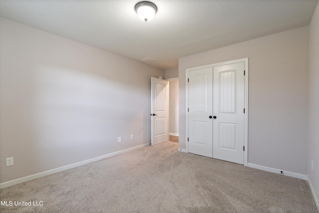unfurnished bedroom with carpet flooring, a closet, and baseboards