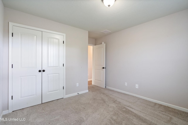 unfurnished bedroom with carpet floors, a closet, and baseboards