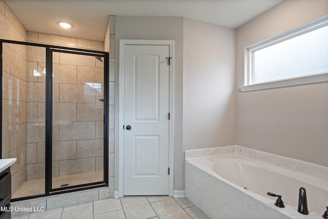 full bathroom featuring a stall shower, a garden tub, vanity, and tile patterned floors