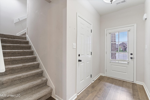 foyer entrance featuring stairs, wood-type flooring, and baseboards