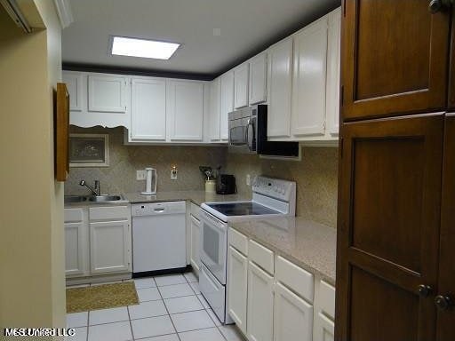 kitchen with white appliances, backsplash, and white cabinetry