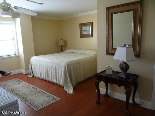 bedroom featuring dark wood-type flooring, crown molding, and ceiling fan