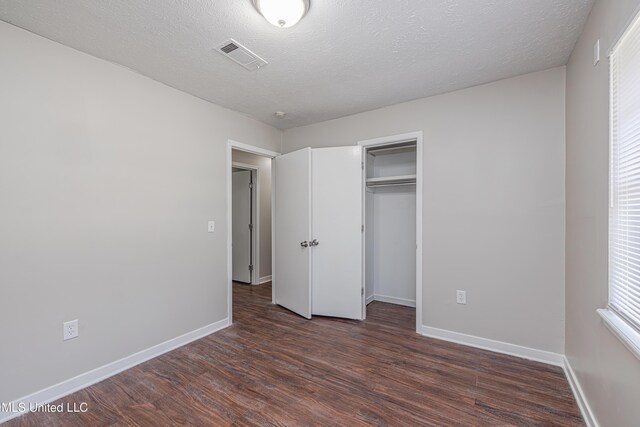 27 Wisteria Ct, Jackson, MS 39204 - unfurnished bedroom with dark wood-style floors, baseboards, a closet, and a textured ceiling
