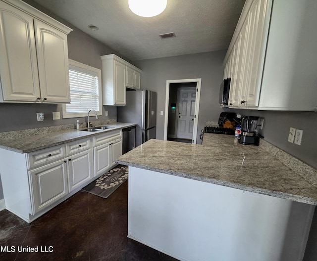 305 Flagstone Dr, Brandon, MS 39042 - kitchen with appliances with stainless steel finishes, a peninsula, white cabinetry, and a textured ceiling
