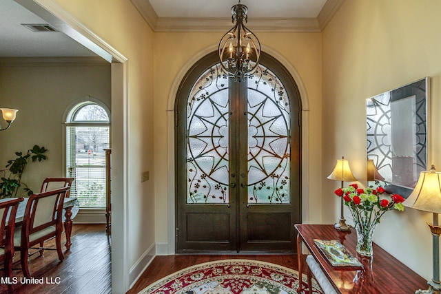 entryway featuring dark wood-style floors, french doors, a notable chandelier, visible vents, and ornamental molding