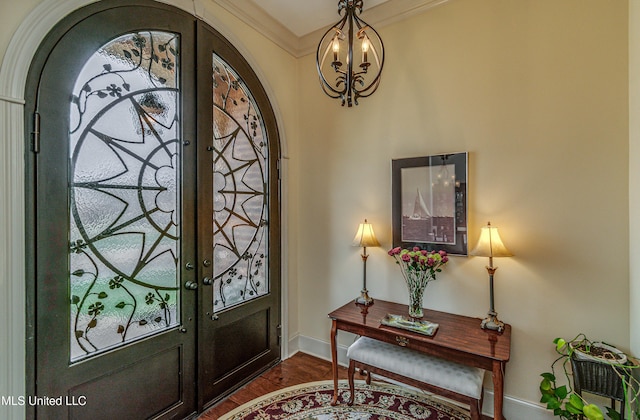 foyer entrance featuring ornamental molding, french doors, dark wood-type flooring, and baseboards