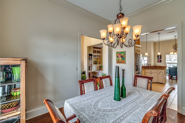 dining space with an inviting chandelier, light wood-style flooring, baseboards, and crown molding