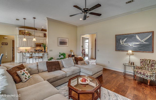 living room with ornamental molding, light wood-type flooring, and visible vents