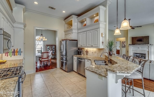 kitchen with a breakfast bar area, open floor plan, a peninsula, stainless steel appliances, and a sink