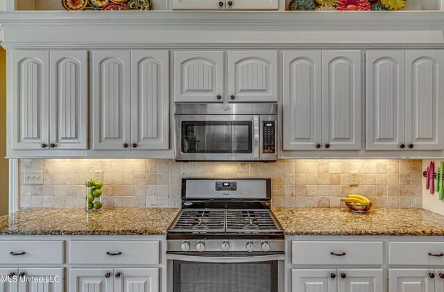 kitchen featuring appliances with stainless steel finishes, white cabinetry, and light stone countertops