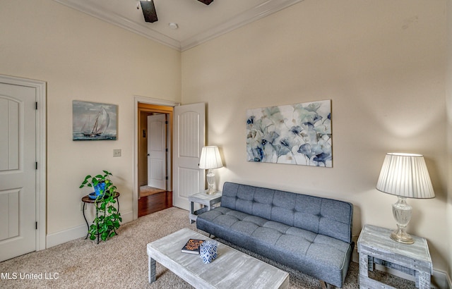 carpeted living area with ornamental molding, a towering ceiling, a ceiling fan, and baseboards