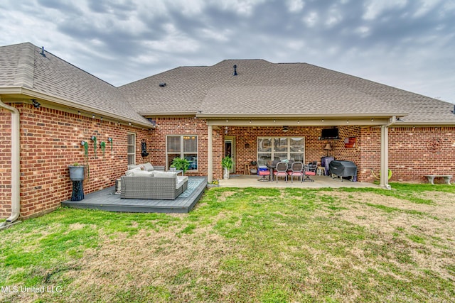 back of property featuring brick siding, a yard, an outdoor hangout area, and roof with shingles