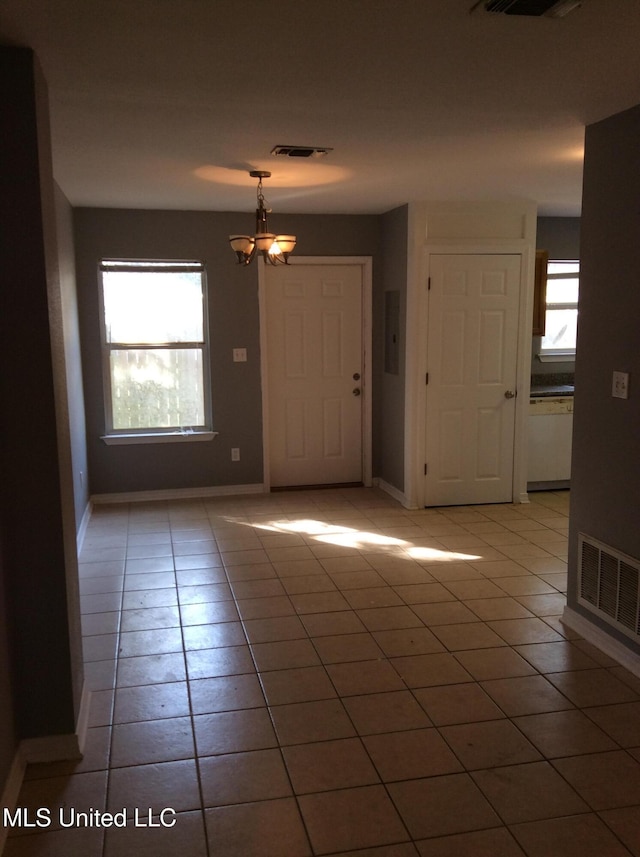 empty room featuring tile patterned floors and a chandelier