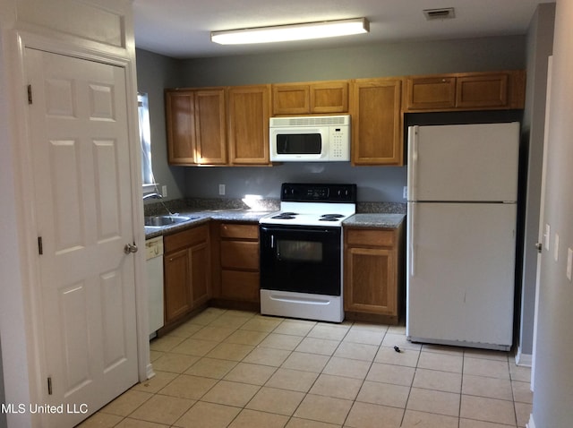 kitchen featuring white appliances, sink, and light tile patterned floors