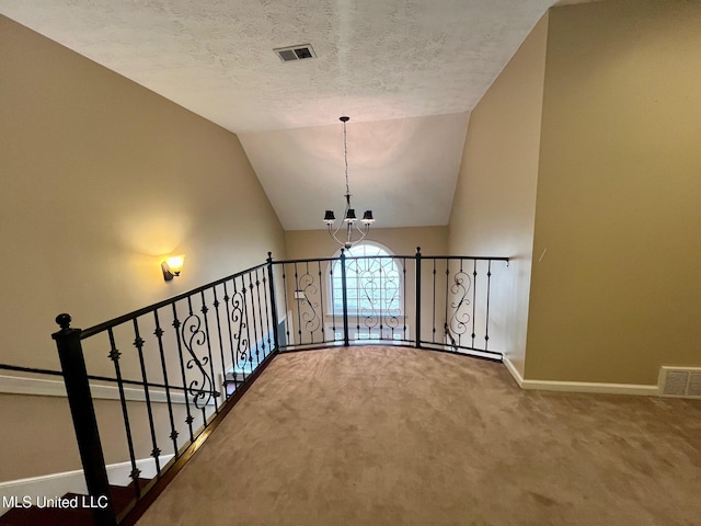 corridor with a textured ceiling, carpet floors, visible vents, baseboards, and an inviting chandelier