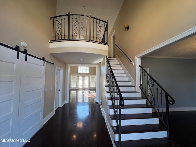 staircase featuring baseboards, arched walkways, a towering ceiling, wood finished floors, and french doors