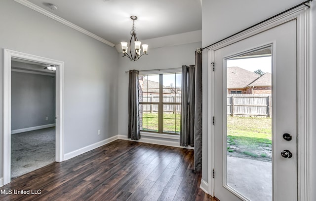 unfurnished dining area with dark wood finished floors, crown molding, a notable chandelier, and baseboards