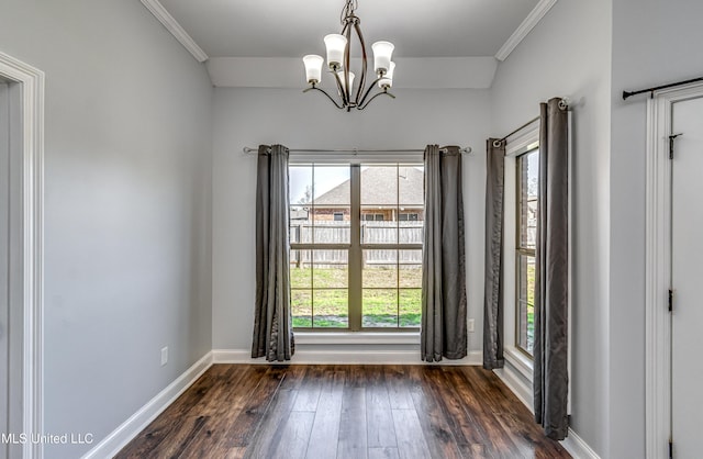 spare room featuring crown molding, a notable chandelier, dark wood-style floors, and baseboards