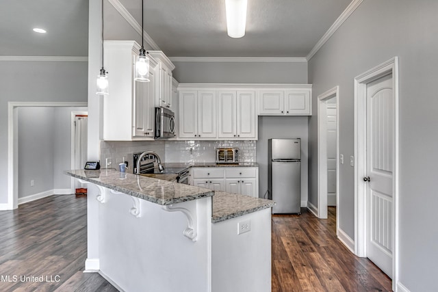 kitchen with a kitchen breakfast bar, appliances with stainless steel finishes, a peninsula, and white cabinets