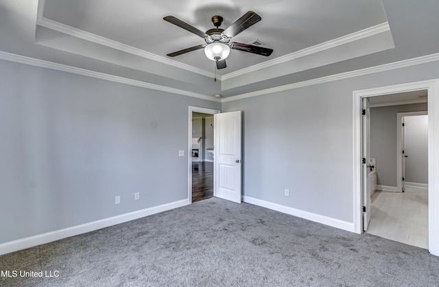 unfurnished bedroom with crown molding, baseboards, a tray ceiling, carpet floors, and a ceiling fan