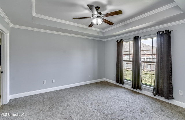 empty room featuring a tray ceiling, carpet floors, baseboards, and a ceiling fan