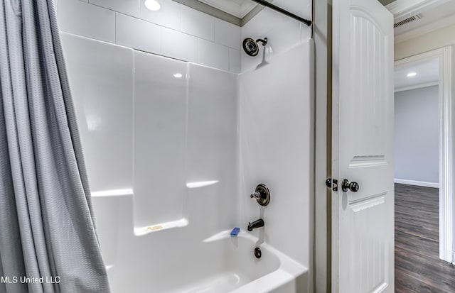 bathroom with wood finished floors, shower / bathtub combination with curtain, and visible vents