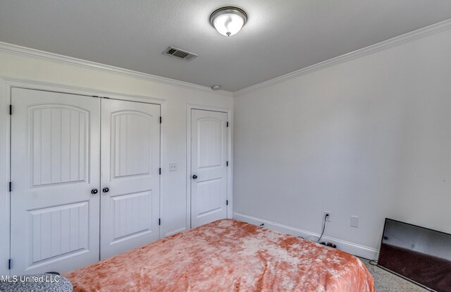 bedroom featuring a closet, baseboards, visible vents, and ornamental molding