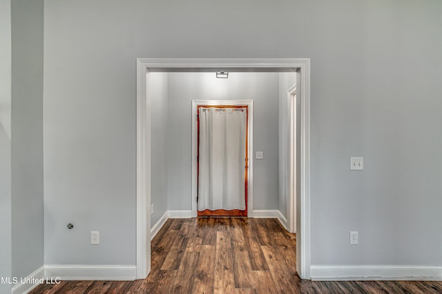 hallway with dark wood-type flooring and baseboards