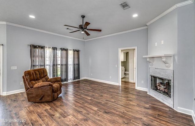 living area with visible vents, a tile fireplace, crown molding, and wood finished floors