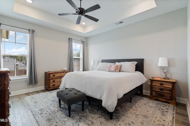 bedroom featuring hardwood / wood-style flooring, a raised ceiling, and ceiling fan