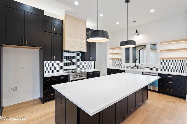 kitchen featuring stainless steel appliances, backsplash, hanging light fixtures, and light wood-type flooring