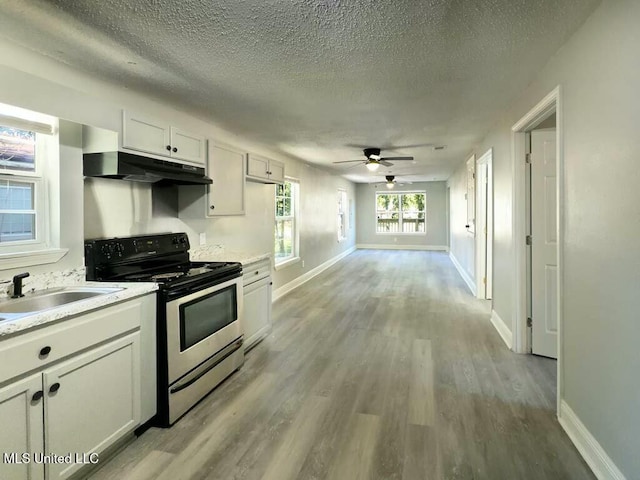 kitchen featuring white cabinetry, stainless steel electric range, a textured ceiling, light hardwood / wood-style flooring, and sink