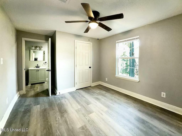 unfurnished bedroom featuring dark wood-type flooring, ceiling fan, a textured ceiling, and sink