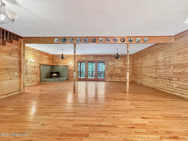 159 Vard Sullivan Rd, Pinola, MS 39149 - unfurnished living room with an inviting chandelier, wood walls, wood finished floors, and a fireplace