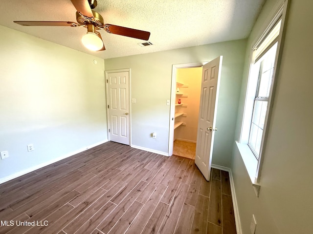2006 Eden St, Pascagoula, MS 39581 - unfurnished bedroom with dark wood-style floors, multiple windows, baseboards, a closet, and a textured ceiling