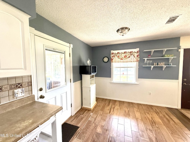 2006 Eden St, Pascagoula, MS 39581 - unfurnished dining area with a textured ceiling, wood finished floors, and a wainscoted wall