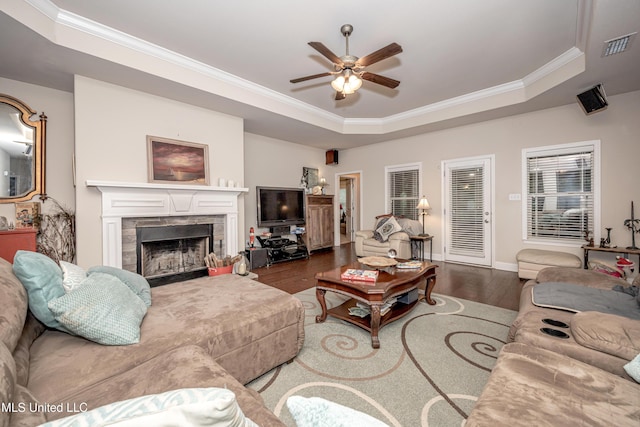 living room with ornamental molding, a ceiling fan, wood finished floors, and a raised ceiling