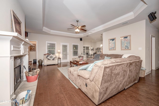 living room with a raised ceiling, wood finished floors, visible vents, a ceiling fan, and a fireplace