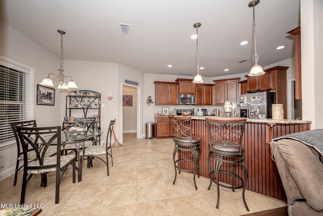 kitchen featuring stainless steel appliances, visible vents, baseboards, a peninsula, and a kitchen bar