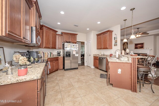 kitchen featuring a ceiling fan, a sink, a breakfast bar area, a peninsula, and appliances with stainless steel finishes