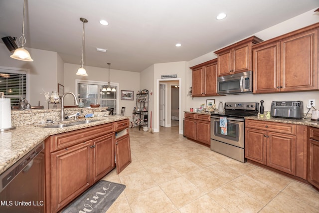 kitchen featuring pendant lighting, a sink, brown cabinets, and appliances with stainless steel finishes