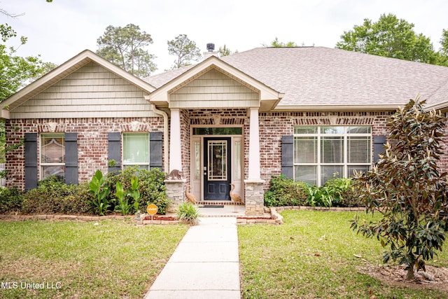 view of front of property with brick siding, a front yard, and roof with shingles