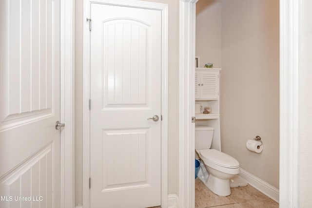 bathroom with toilet, tile patterned floors, and baseboards