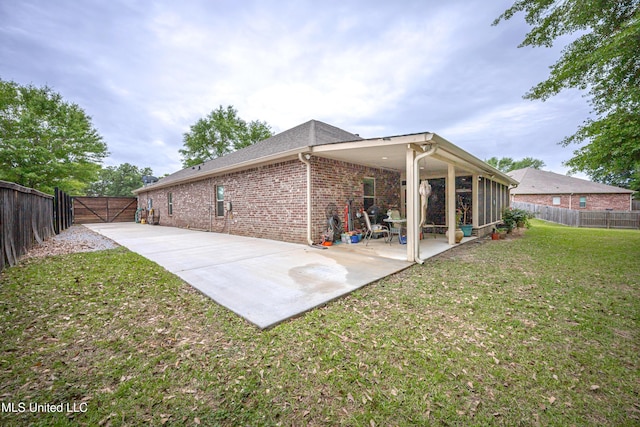 rear view of house with brick siding, a yard, a patio area, and a fenced backyard