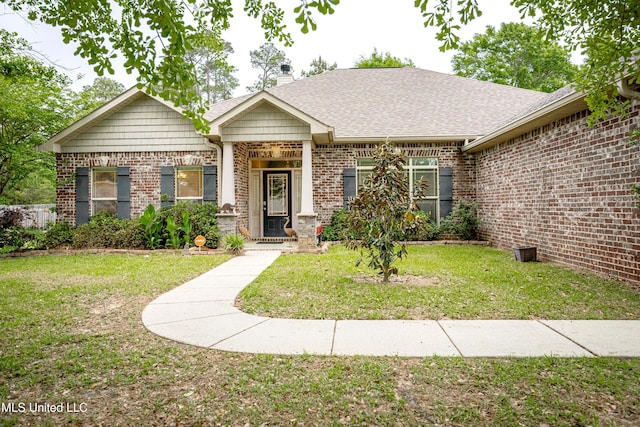 view of front facade with a front lawn, a chimney, brick siding, and roof with shingles