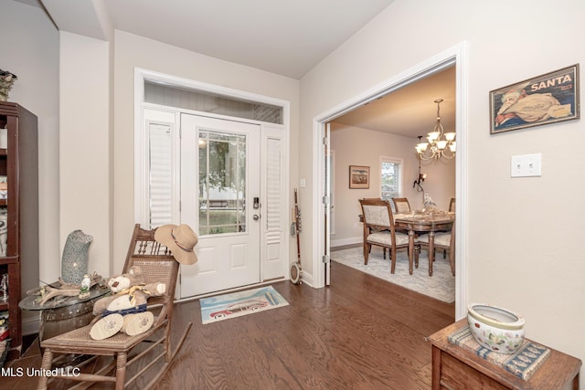 entryway with an inviting chandelier, dark wood-type flooring, and baseboards