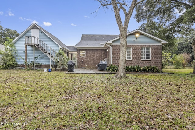 back of house with a patio and a lawn