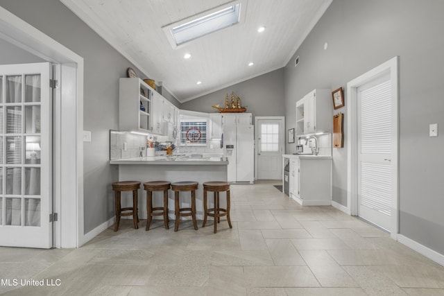 kitchen featuring sink, white cabinetry, tasteful backsplash, white refrigerator with ice dispenser, and kitchen peninsula