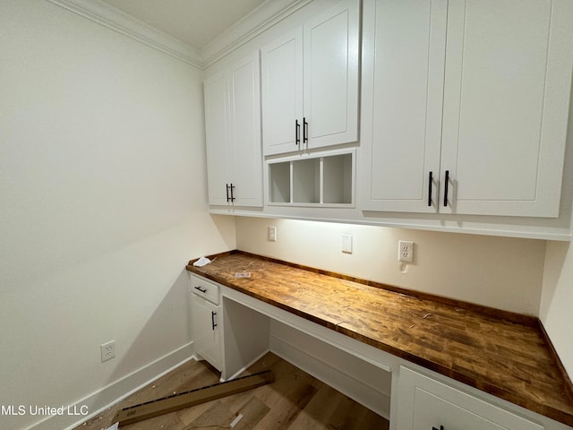 interior space with hardwood / wood-style flooring, ornamental molding, and built in desk